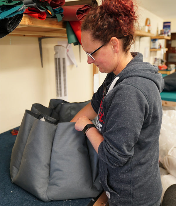 Person adding stuffing to each section of a Tuffies dog bed in our warehouse.