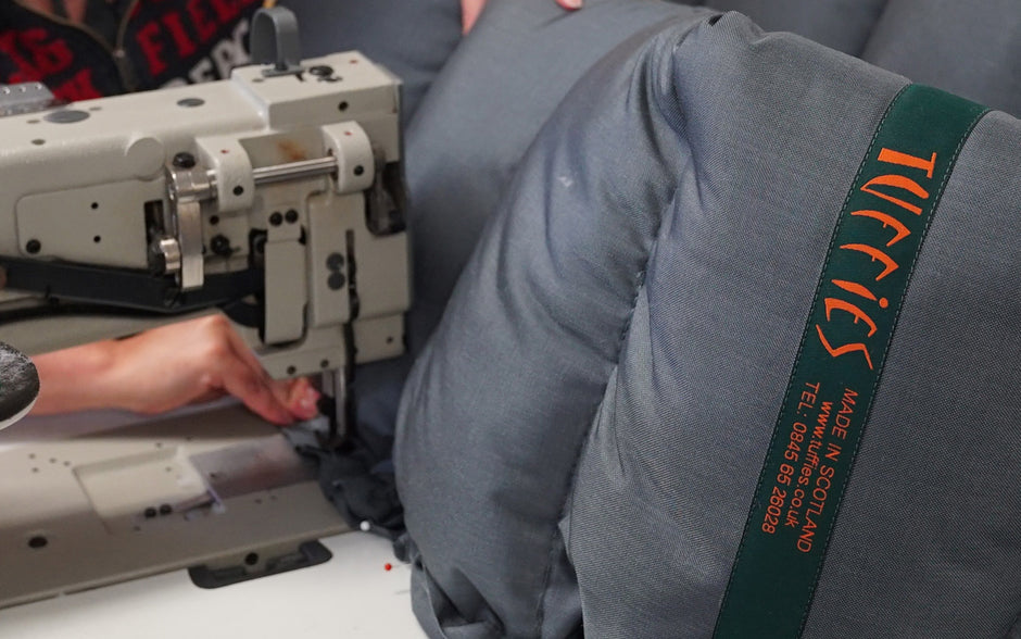 Person operating a sewing machine with a close-up of the machine, person's hands, and a Tuffies orthopaedic nest bed.
